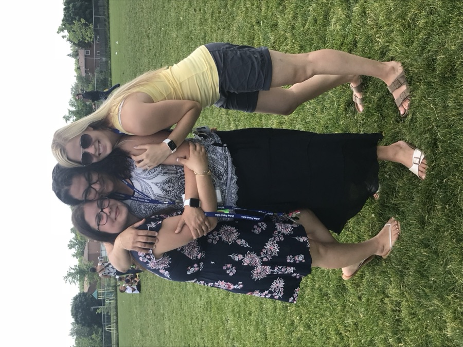 Danielle hugging two colleagues on the field at a school event